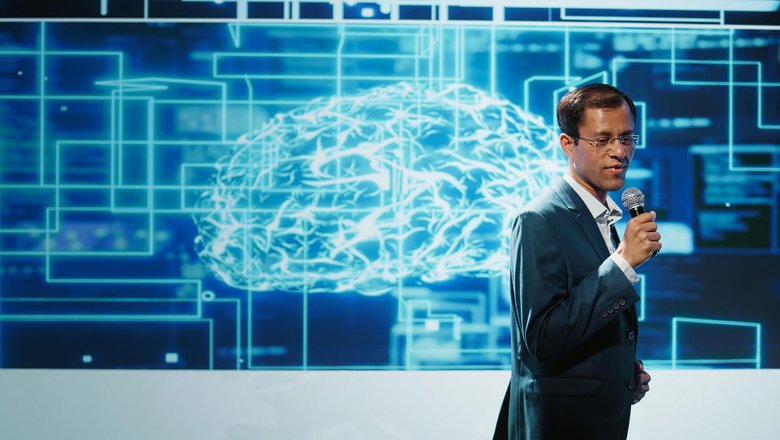 Homme faisant une présentation, cerveau projeté derrière lui sur un écran