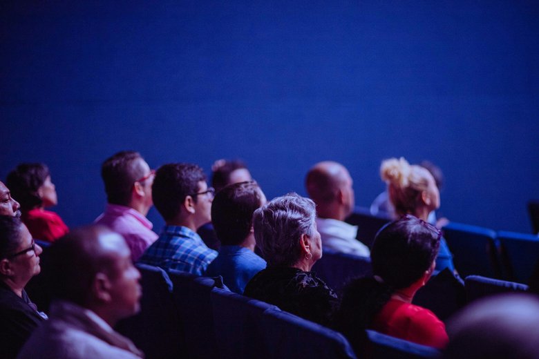 Des personnes assises dans le public dans une salle de conférence