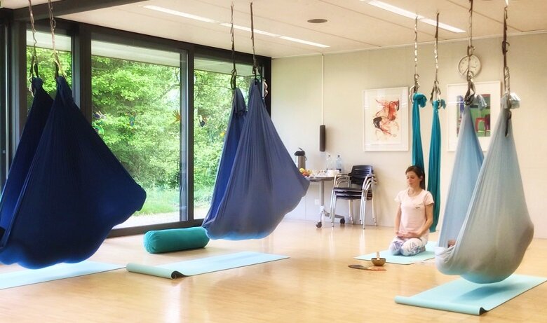 Salle de cours de yoga aérien avec des hamacs et des tapis de sol