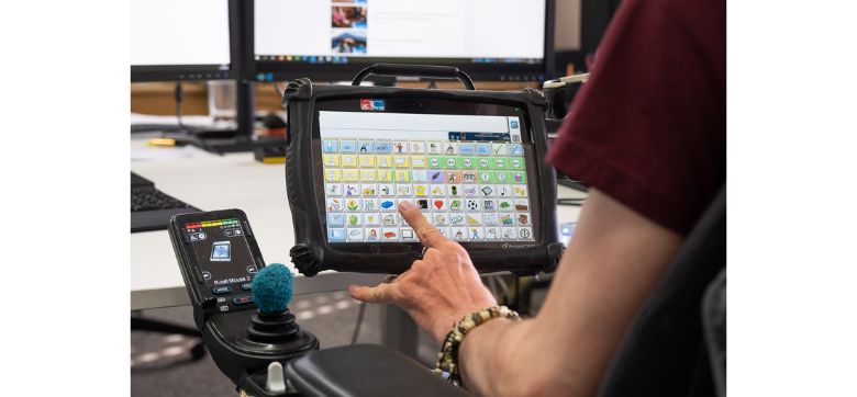 Unterstützte Kommunikation Eine Person berührt einen Bildschirm mit Symbolen.
