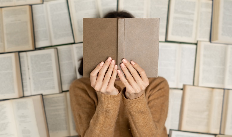Lecture Une femme tient un livre ouvert devant son visage
