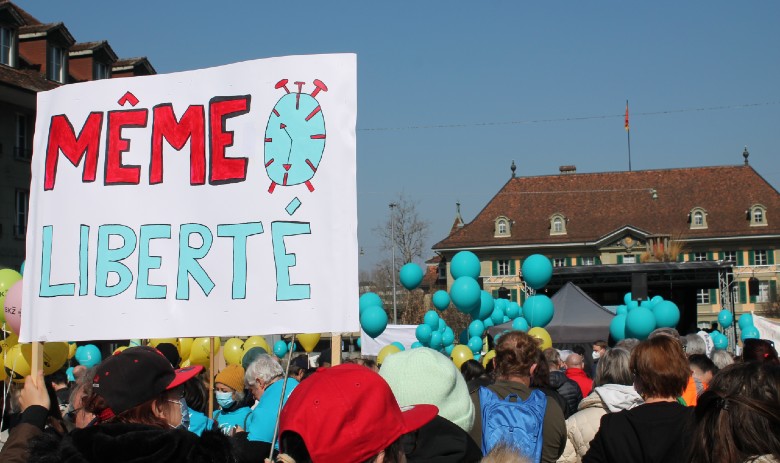 Eine Ansammlung von vielen Menschen. Im Vordergrund wird ein Schild hochgehalten auf dem Steht "Même Liberté"